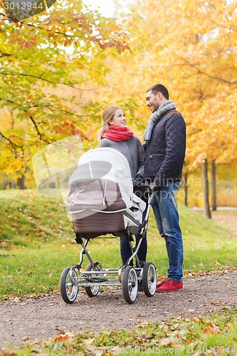 Image of smiling couple with baby pram in autumn park