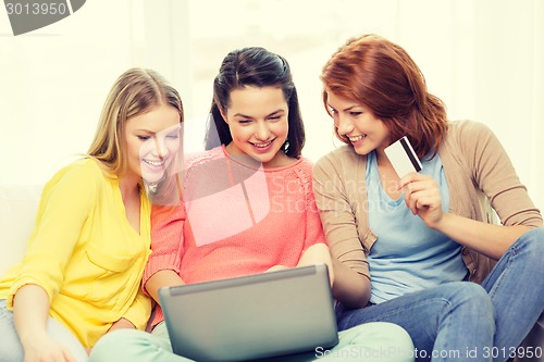 Image of smiling teenage girls with laptop and credit card