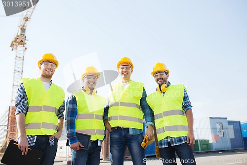 Image of group of smiling builders with tablet pc outdoors