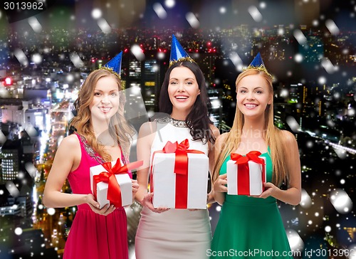 Image of smiling women in party caps with gift boxes