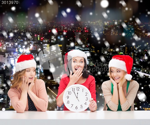 Image of smiling women in santa helper hats with clock