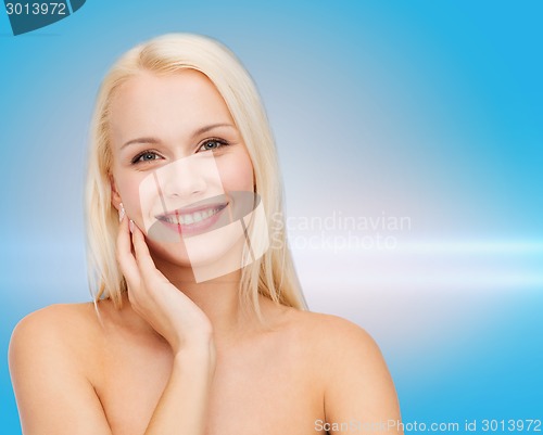 Image of smiling young woman touching her face skin