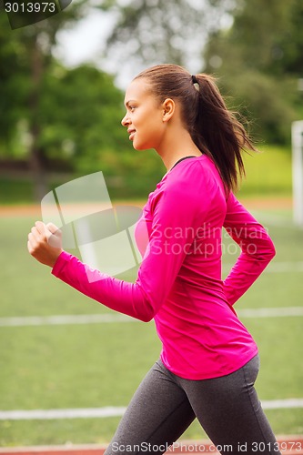 Image of smiling woman running on track outdoors