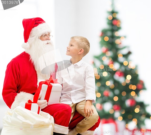 Image of smiling little boy with santa claus and gifts
