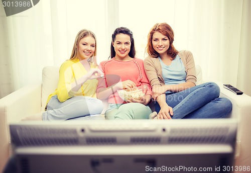 Image of three smiling teenage girl watching tv at home
