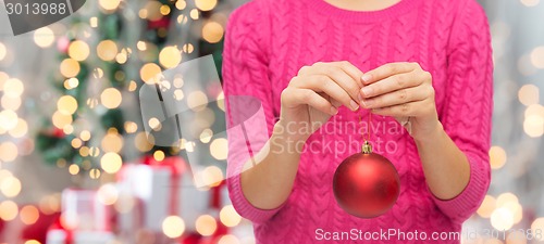 Image of close up of woman in sweater with christmas ball