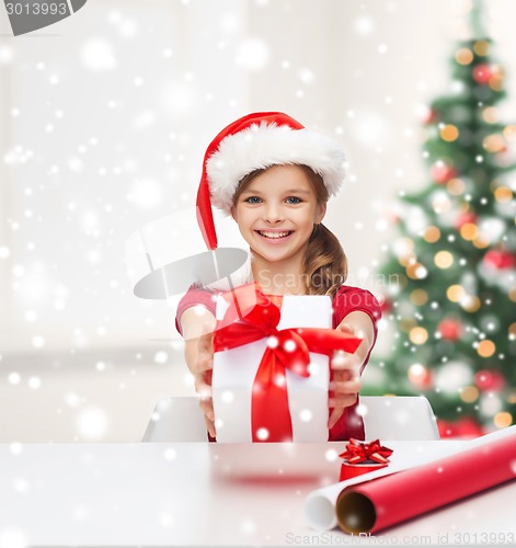 Image of smiling girl in santa helper hat with gift box