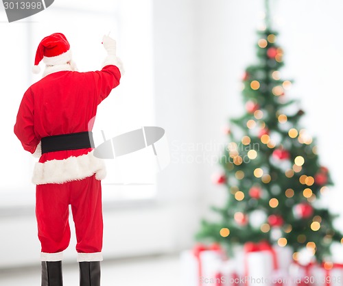 Image of man in costume of santa claus writing something