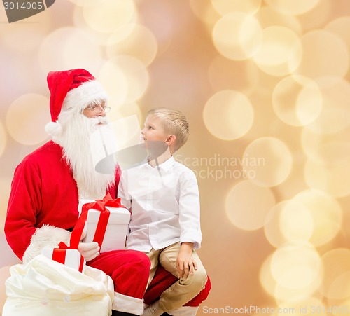 Image of smiling little boy with santa claus and gifts