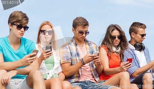 Image of group of friends with smartphones outdoors