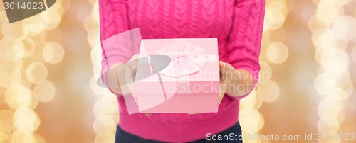 Image of close up of woman in pink sweater holding gift box