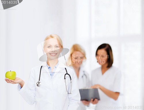 Image of smiling female doctor with green apple