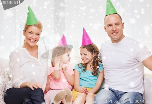 Image of happy family with two kids in party hats at home