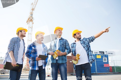 Image of group of smiling builders with tablet pc outdoors