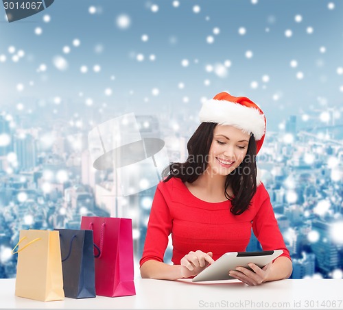 Image of smiling woman with shopping bags and tablet pc