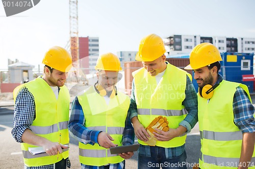 Image of group of smiling builders with tablet pc outdoors