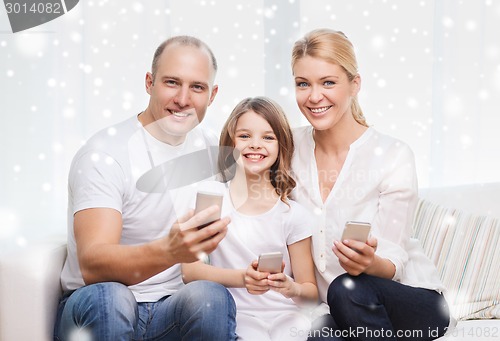 Image of happy family with smartphones at home