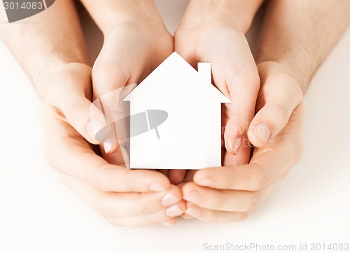 Image of man and woman hands with white paper house