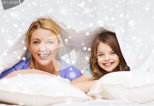 Image of happy mother and girl under blanket at home