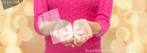 Image of close up of woman in sweater holding snowflake