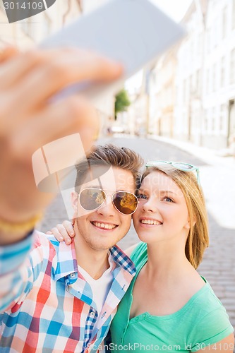 Image of smiling couple with smartphone in city