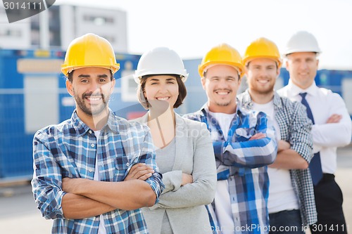 Image of group of smiling builders in hardhats outdoors