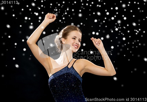 Image of smiling woman dancing with raised hands