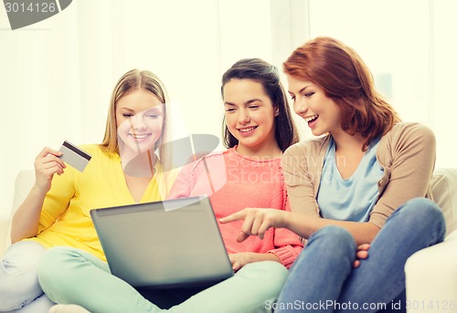 Image of smiling teenage girls with laptop and credit card