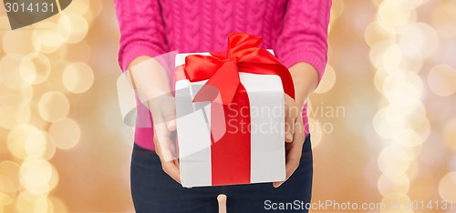 Image of close up of woman in pink sweater holding gift box