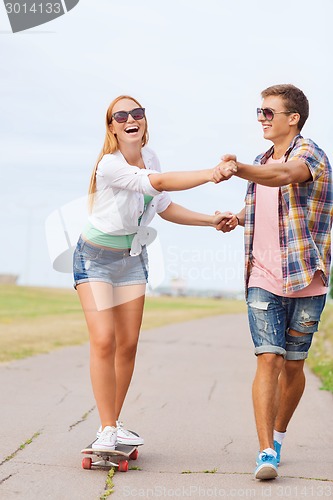 Image of smiling couple with skateboard outdoors