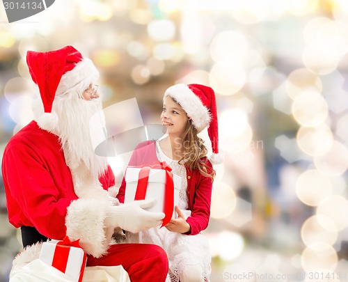 Image of smiling little girl with santa claus and gifts