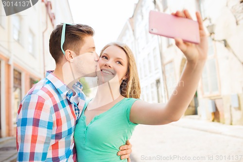 Image of smiling couple with smartphone in city