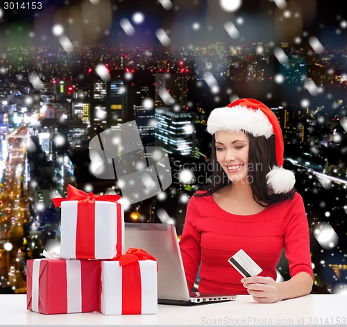 Image of smiling woman with gifts, laptop and credit card