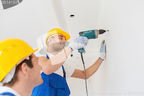 Image of group of smiling builders with drill indoors