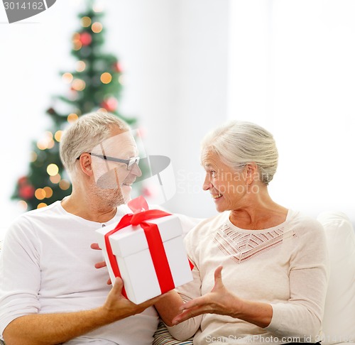 Image of happy senior couple with gift box at home