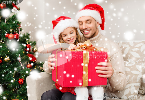 Image of smiling father and daughter with gift box at home