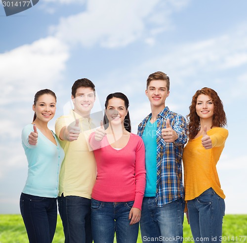 Image of group of smiling teenagers over blue sky and grass