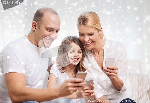 Image of happy family with smartphones at home