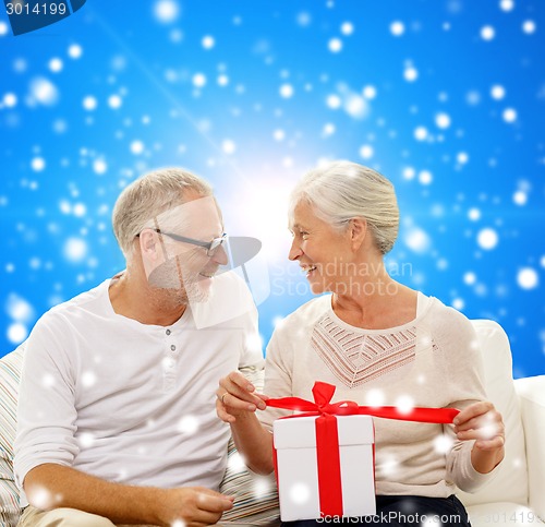 Image of happy senior couple with gift box at home