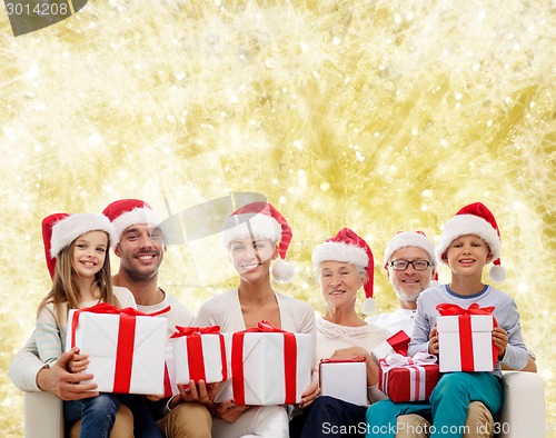 Image of happy family in santa helper hats with gift boxes