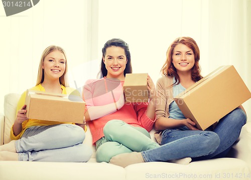 Image of smiling teenage girls with cardboard boxes at home