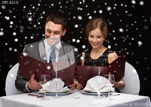 Image of smiling couple with menus at restaurant