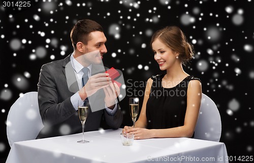 Image of smiling couple with red gift box at restaurant