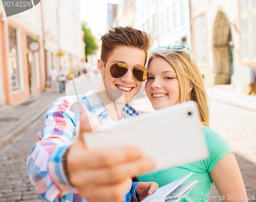 Image of smiling couple with smartphone in city