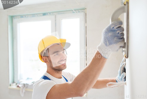 Image of smiling builder working with grinding tool indoors