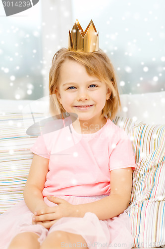 Image of smiling little girl in crown sitting on sofa