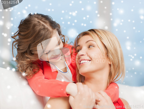 Image of happy mother and daughter hugging at home