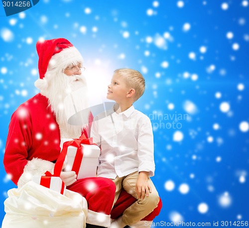 Image of smiling little boy with santa claus and gifts