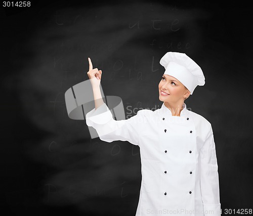 Image of smiling female chef pointing finger to something