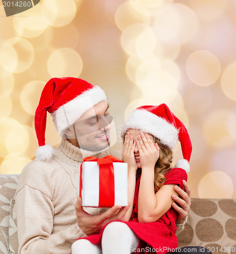 Image of smiling daughter waiting for present from father